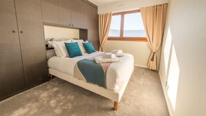 Un dormitorio con cama, armario, ventana con cortinas y vista al exterior.