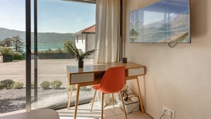 Een kamer met een bureau, stoel en een groot raam met uitzicht op een meer en bergen.