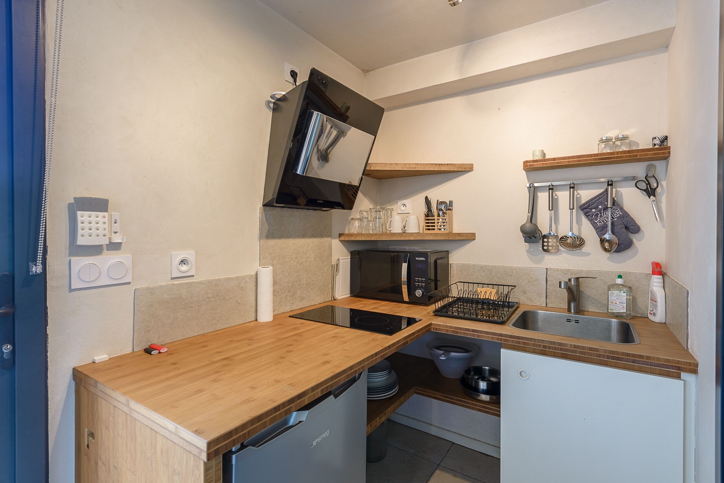 Une cuisine compacte équipée d’un four à micro-ondes, d’une cuisinière, d’un évier et d’un plan de travail en bois.