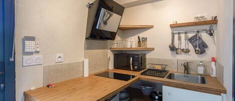 Une cuisine compacte équipée d’un four à micro-ondes, d’une cuisinière, d’un évier et d’un plan de travail en bois.