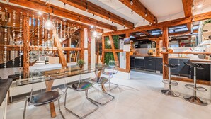 Una cucina moderna con travi in legno, un tavolo da pranzo in vetro e sgabelli da bar.
