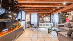 Un soggiorno moderno con soffitto in legno, un tavolino in vetro, un divano e una poltrona.