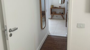 Um corredor com porta de madeira, tapete marrom e espelho na parede.