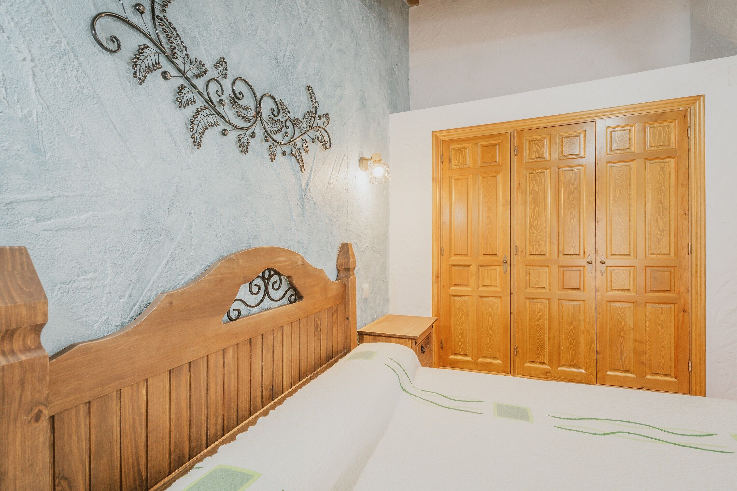 A bedroom with a wooden bed, a wardrobe, and a decorative wall piece.