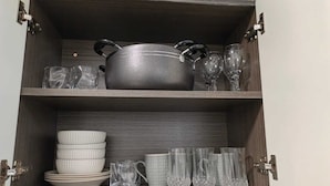 Et køkkenskab med en gryde, vinglas, tallerkener og kopper.
