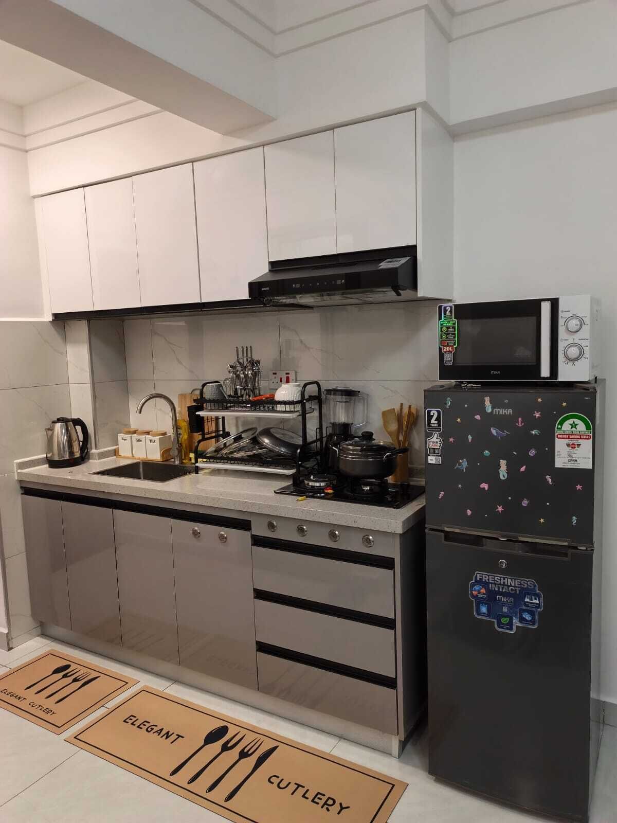 A modern kitchen with a microwave, stove, and refrigerator, featuring stainless steel appliances and a tiled backsplash.