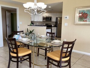 A dining area with a glass table, wooden chairs, and a chandelier.