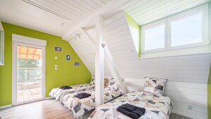 Ein Schlafzimmer mit zwei Betten, einer Schiebetür aus Glas und einer geneigten Decke.