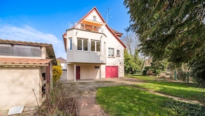 Ein zweistöckiges Haus mit roter Tür, einem sichtbaren Garage und einer befestigten Auffahrt zum Eingang.