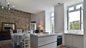 Eine moderne Küche mit einer zentralen Kochinsel, einem Essbereich mit Tisch und Stühlen sowie einem großen Fenster mit Aussicht.