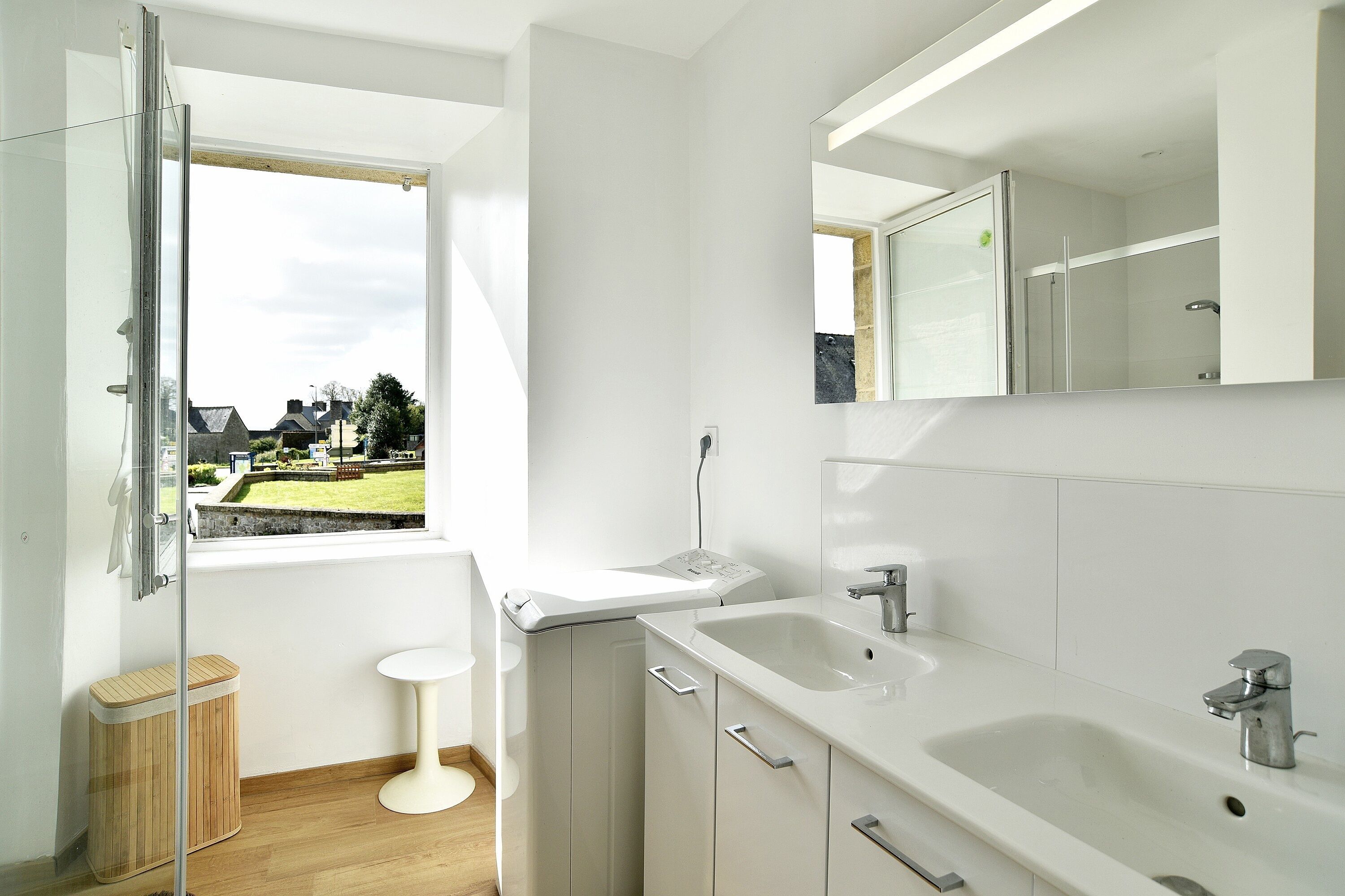 A modern bathroom with a large window, a sink, and a mirror.