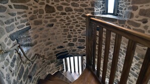 Eine Steintreppe mit hölzernem Geländer und einem kleinen Fenster oben.