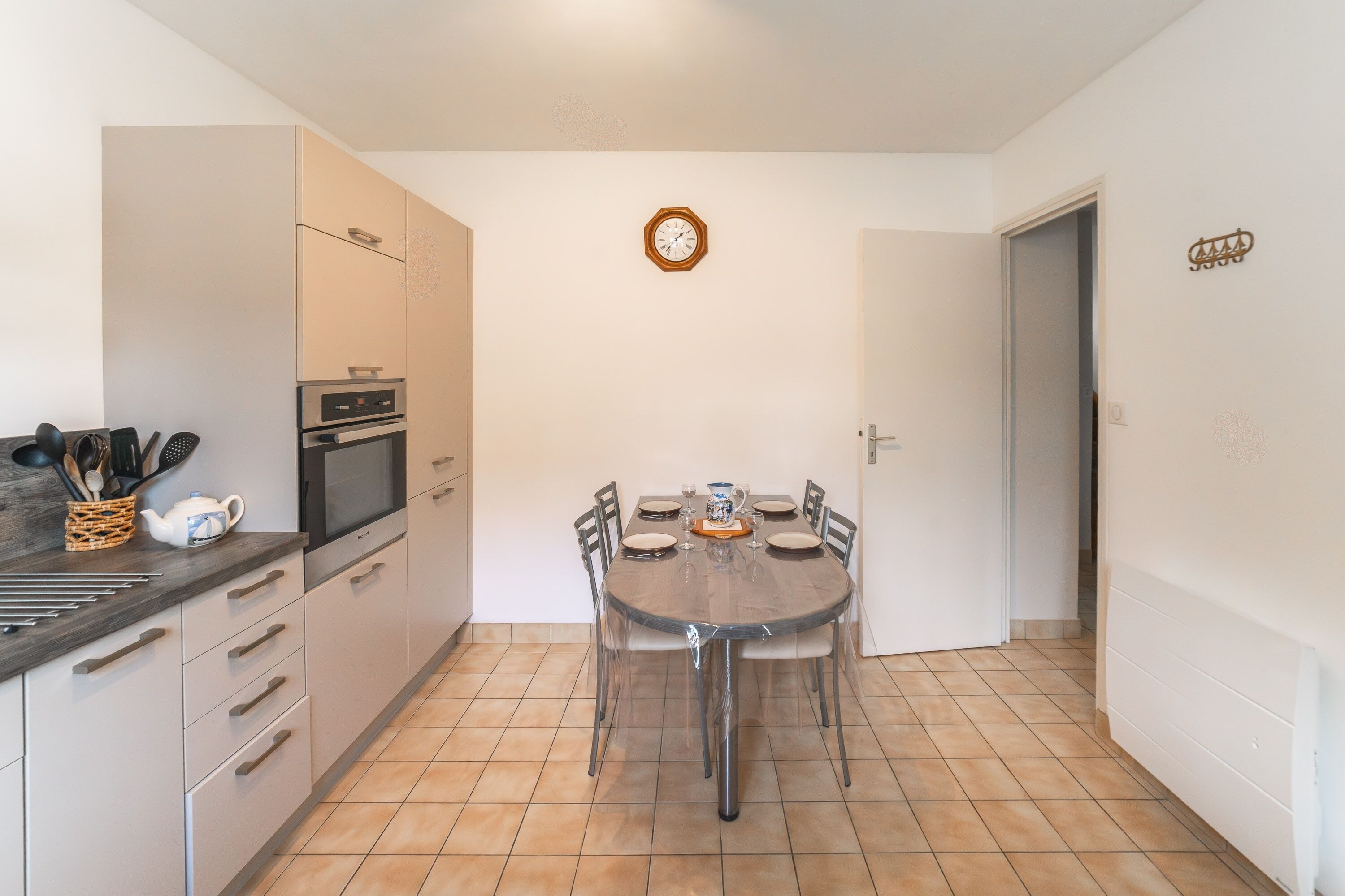Una cocina compacta con una mesa de comedor, armarios y un reloj en la pared.
