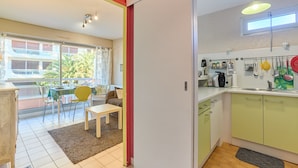 Eine Küche mit Fenster, ein Essbereich mit Tisch und Stühlen sowie der Blick auf ein Gebäude.