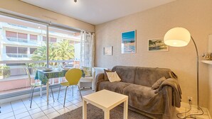Ein Wohnzimmer mit Sofa, Tisch, Lampe und einem Balkon mit Tisch und Stühlen.