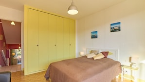 Ein Schlafzimmer mit einem Bett, einem gelben Kleiderschrank, einem Nachttisch und einer Lampe.
