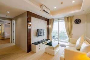 Ein modernes Wohnzimmer mit einem Flachbildfernseher, einem Glastisch, einer Couch, einem Balkon mit Vorhängen und einer Wanduhr.