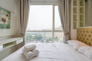 Ein Hotelzimmer mit großem Fenster, einem Bett mit weißer Bettwäsche, einem Kopfteil und einem Nachttisch.