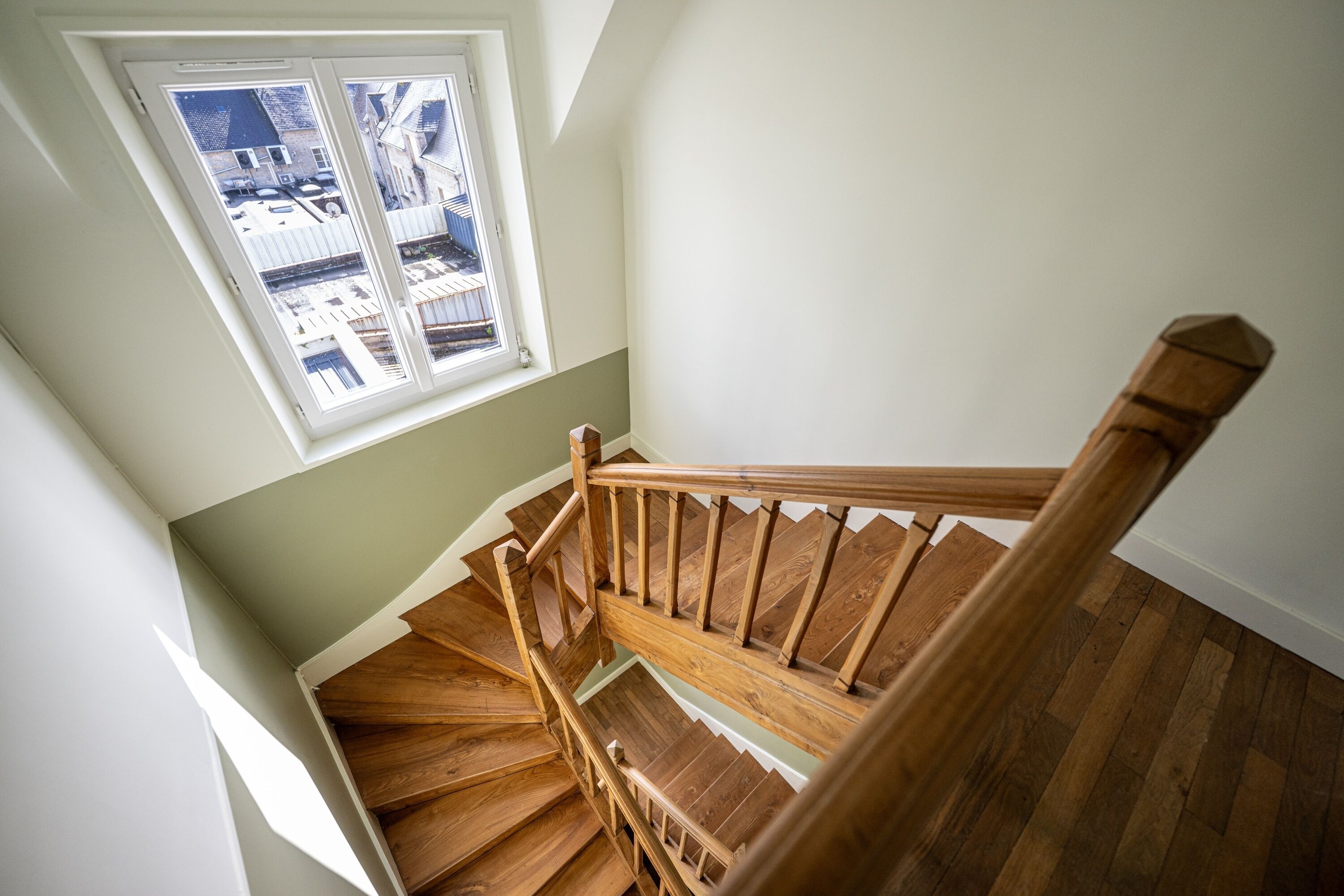 A wooden staircase with a view of the outside through a window.