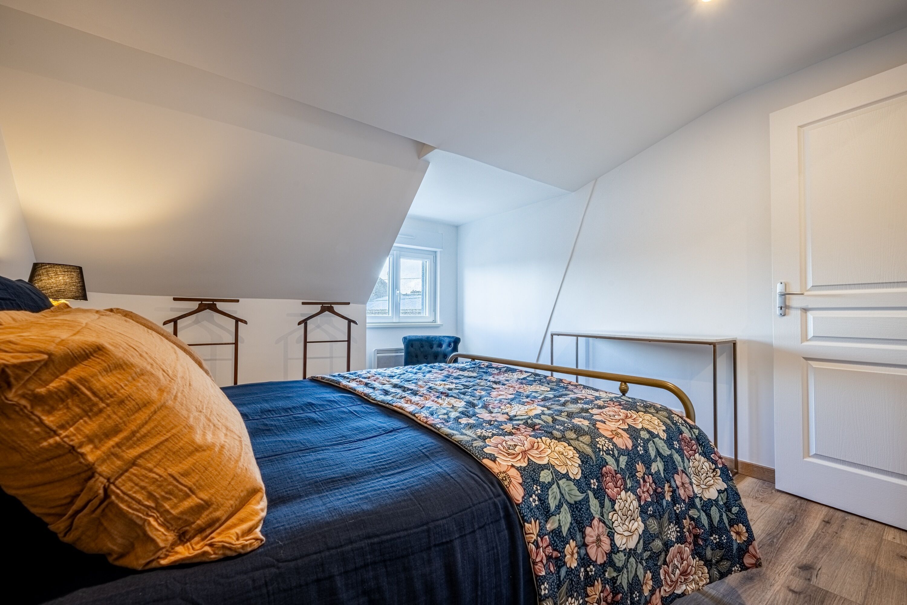 A bedroom with a bed, a window, a door, and a small table.