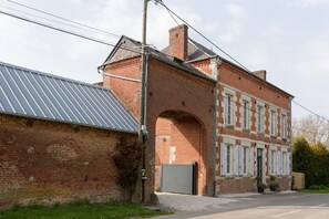 Un edificio de ladrillo con techo metálico, un gran arco de entrada y una puerta de garaje gris cerrada.