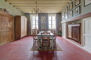 A dining room with a wooden table and chairs, a chandelier, and a patterned rug.
