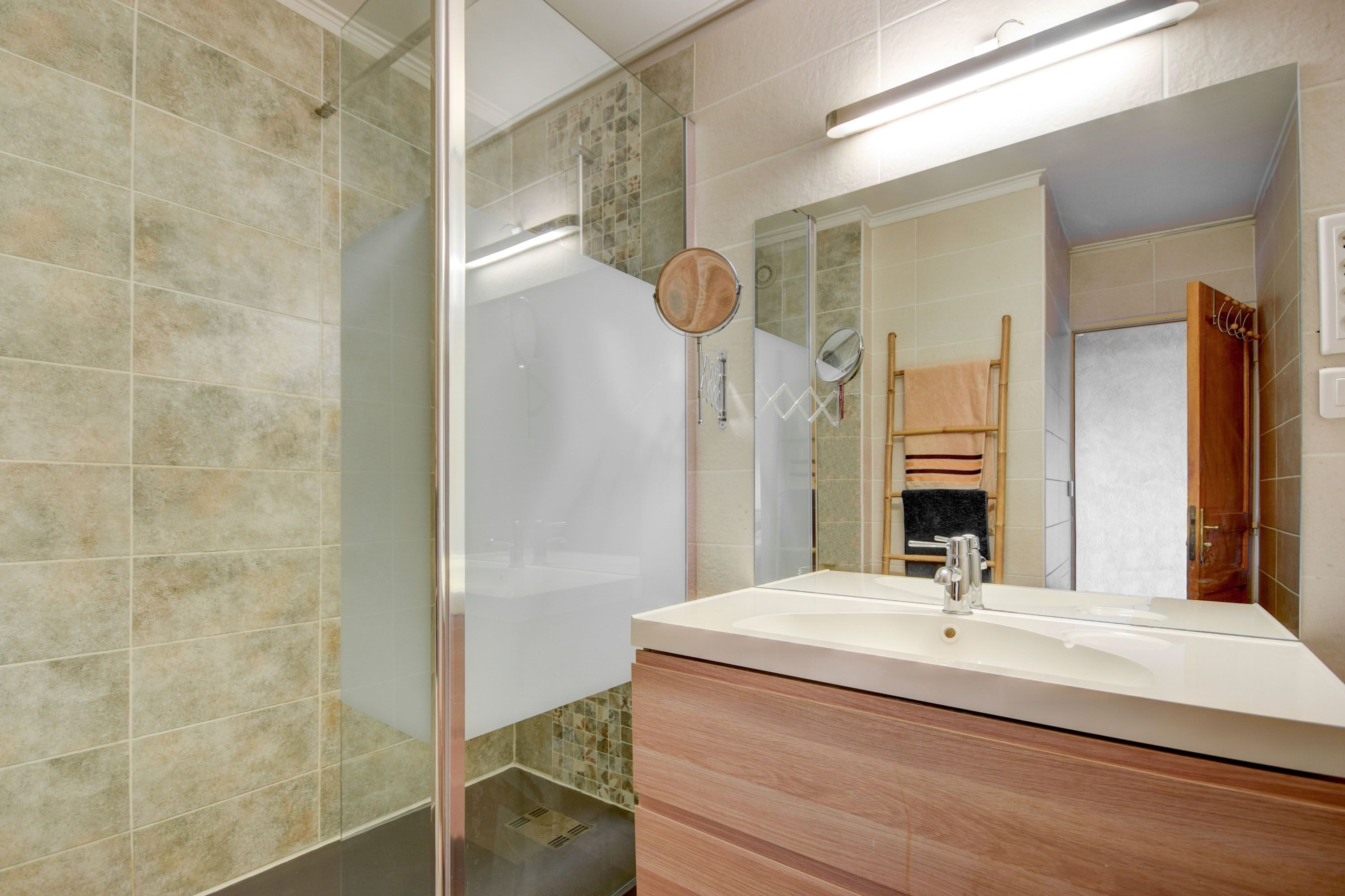 Un baño con cabina de ducha de vidrio, un lavabo con espejo y un mueble de tocador de madera.