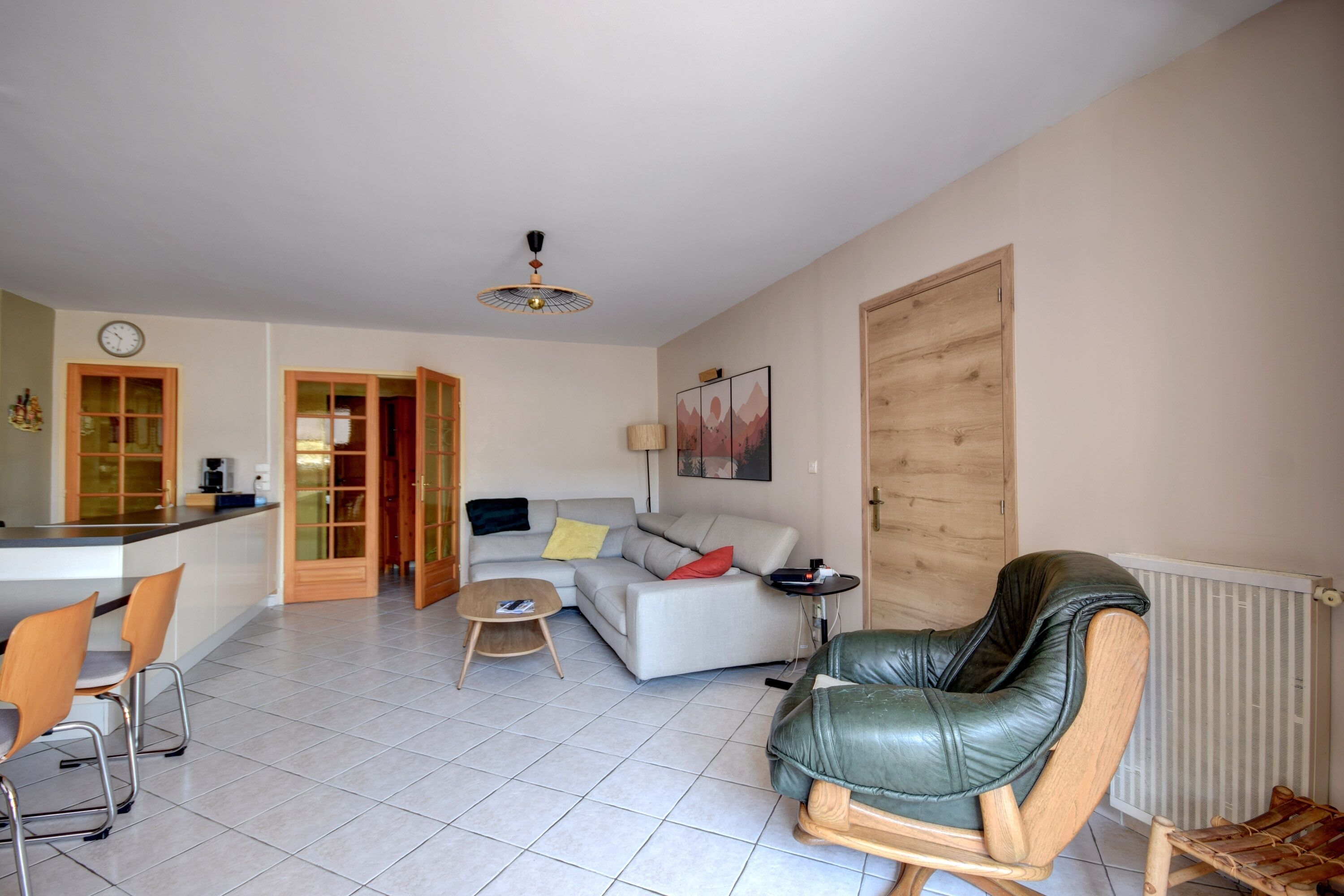 Una sala de estar con un sofá, un sillón de cuero, una mesa de centro y un comedor con sillas.