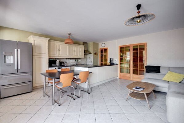 A modern kitchen with a dining area, a sofa, and a coffee table.