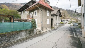 Une rue étroite bordée de bâtiments traditionnels, avec un clocher d’église et une chaîne de montagnes en arrière-plan.