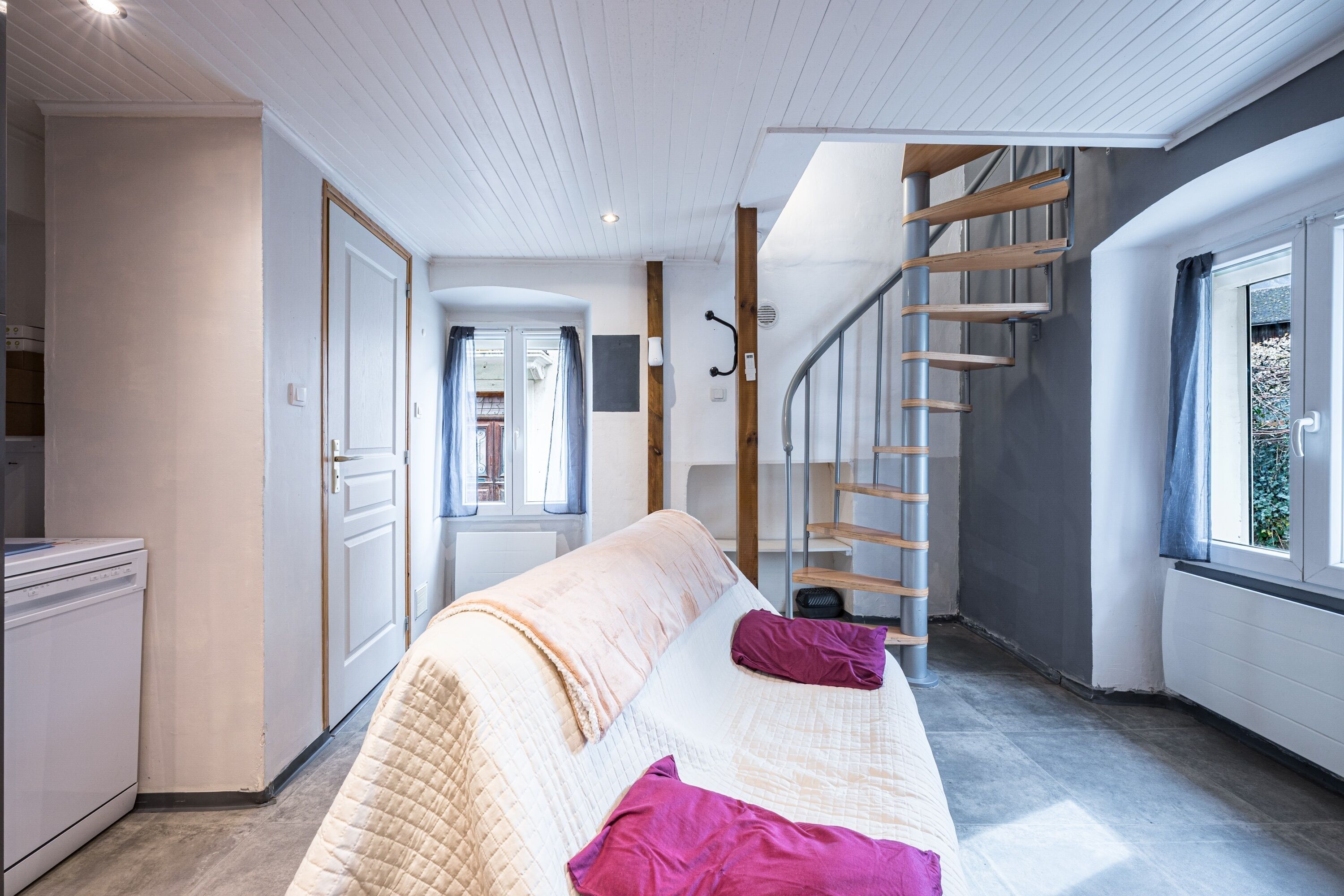 Een slaapkamer met een bed, een trap en een raam.