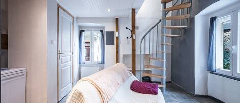 Een slaapkamer met een bed, een trap en een raam.
