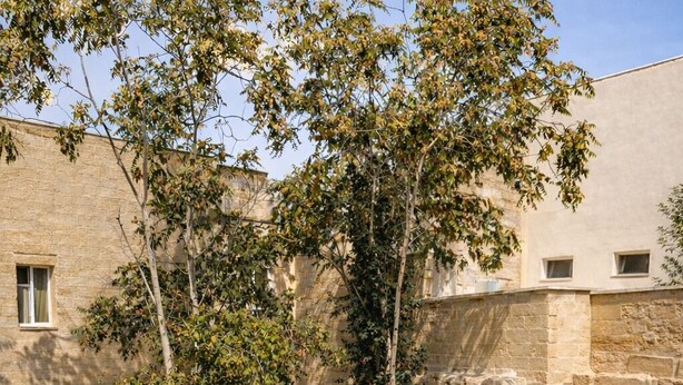 Un patio con piscina, sillas de descanso y un edificio de piedra.