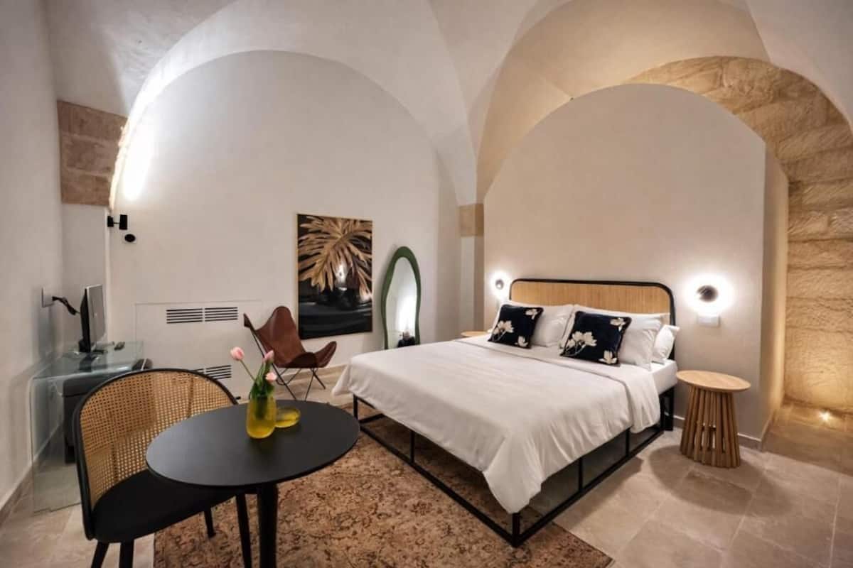 A modern bedroom with a bed, bedside table, and a small round table with chairs.