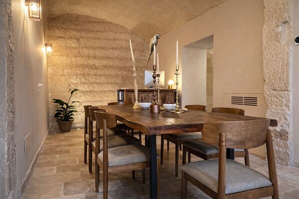 Un coin repas rustique avec un mur en pierre, une table en bois et des chaises.