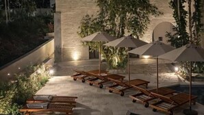 Un edificio moderno con patio, mobiliario exterior y piscina.