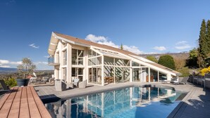 Una casa moderna con piscina, ventanas amplias y una terraza.