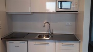 Une cuisine compacte équipée d’un four à micro-ondes, d’un évier et d’un lave-vaisselle.