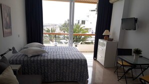 Une chambre d’hôtel comprenant un lit, un bureau, une chaise, une télévision et un balcon avec vue sur la ville.