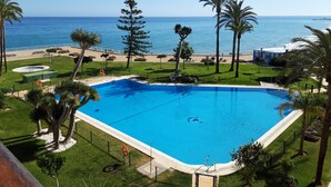 Une piscine avec vue sur l’océan, entourée de palmiers et bordée d’une pelouse bien entretenue.