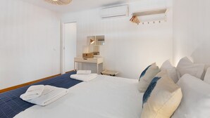 Ein Hotelzimmer mit Bett, Schreibtisch, Spiegel, Klimaanlage und einer Pendelleuchte.
