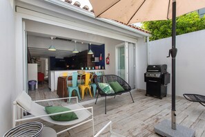 A patio area with outdoor seating, a grill, and a view into the house.