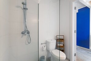 A modern bathroom with a glass shower enclosure, a toilet, and a blue wall.