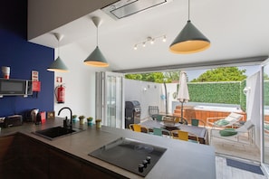 A modern kitchen with a built-in stove, a sink, and a dining area with a table and chairs.