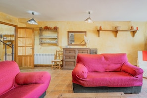 Una sala de estar con dos sofás rojos, una mesa de centro de madera, un espejo y una estantería con objetos decorativos.