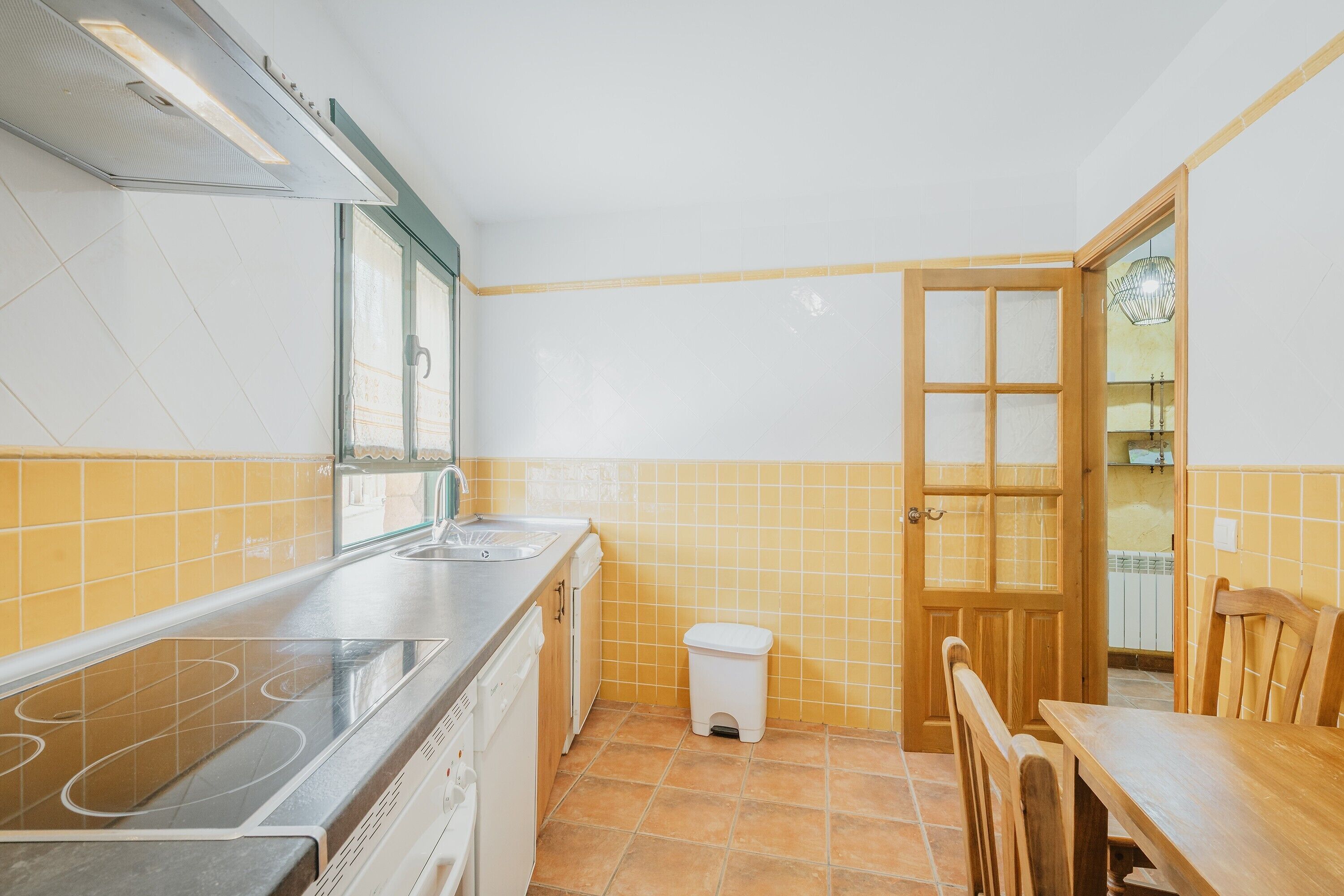 A kitchen with a stove, sink, and wooden table.