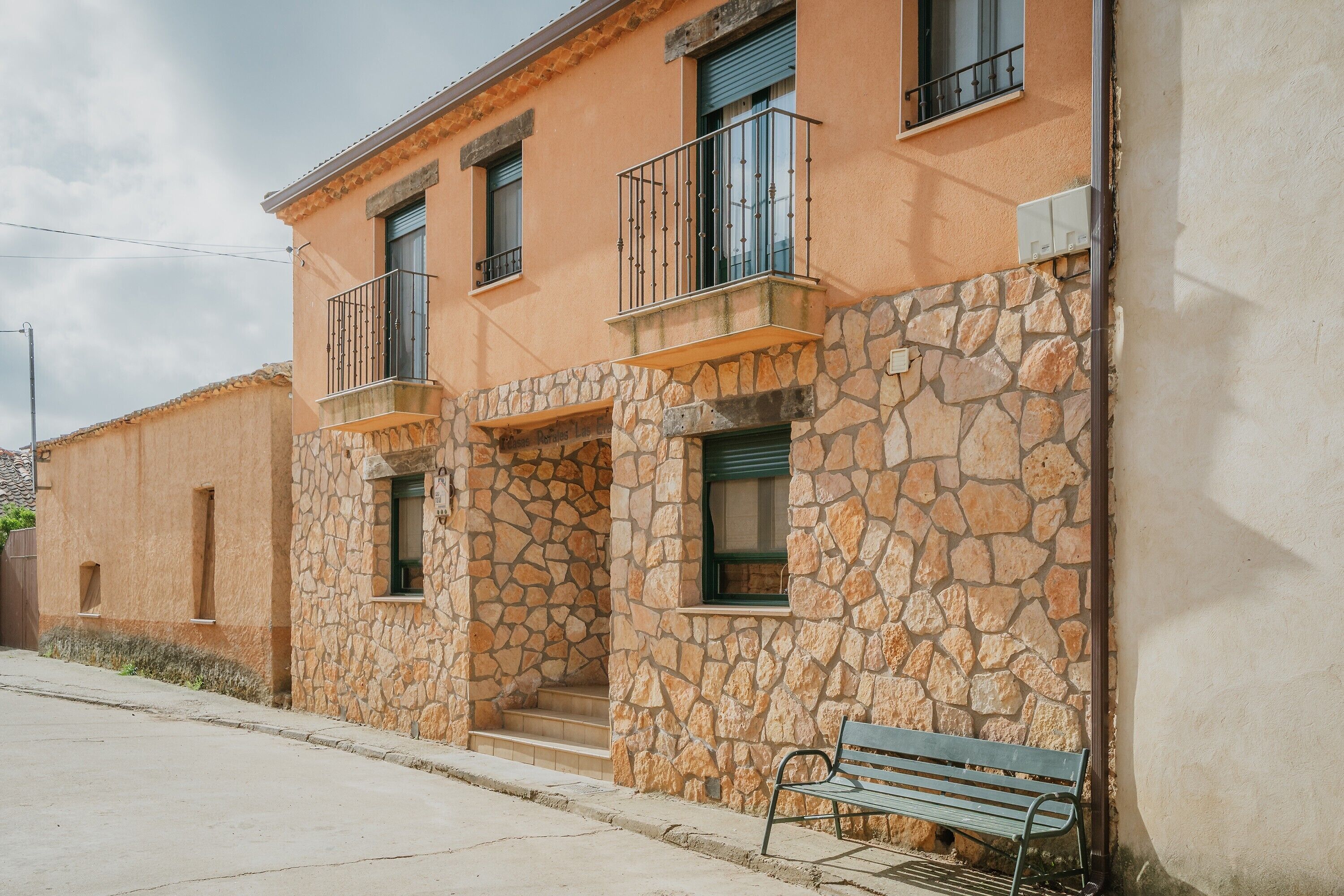 A building with stone walls, balconies, and a bench.