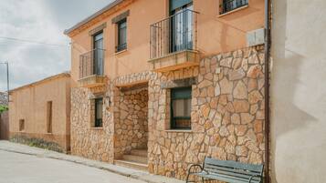 A building with stone walls, balconies, and a bench.