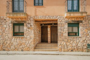 Ein Steinhaus mit einer Holztür, einem Balkon und einem Schild über der Tür.