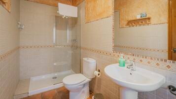 Een badkamer met douche, toilet en wastafel.